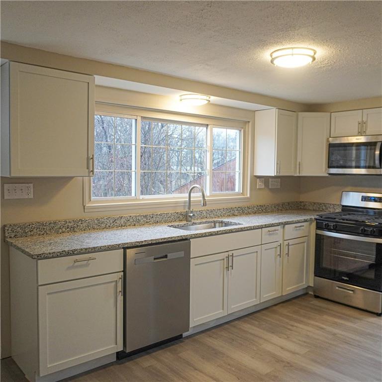 216 Roberts Road Pittsburgh, PA 15239 - Photo 3 of 17 a kitchen with stainless steel appliances granite countertop a sink and a stove next to a large window