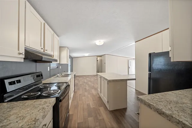 a kitchen with stainless steel appliances granite countertop a refrigerator a stove and a wooden floors