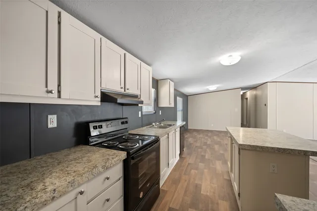 a kitchen with granite countertop a sink a stove and cabinets