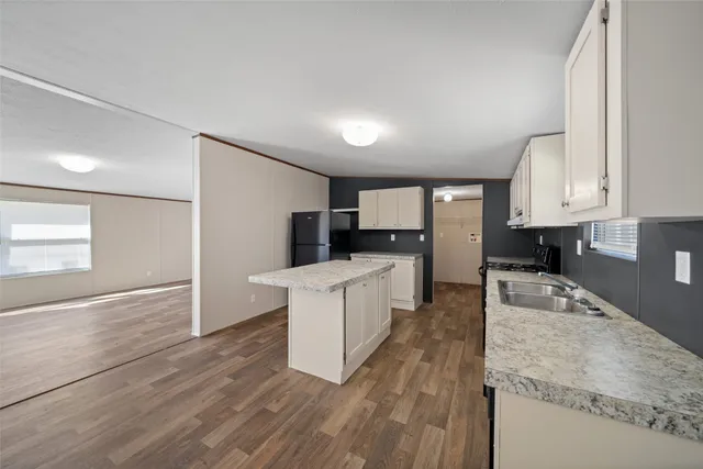 a large kitchen with kitchen island a sink dishwasher stove and white cabinets with wooden floor