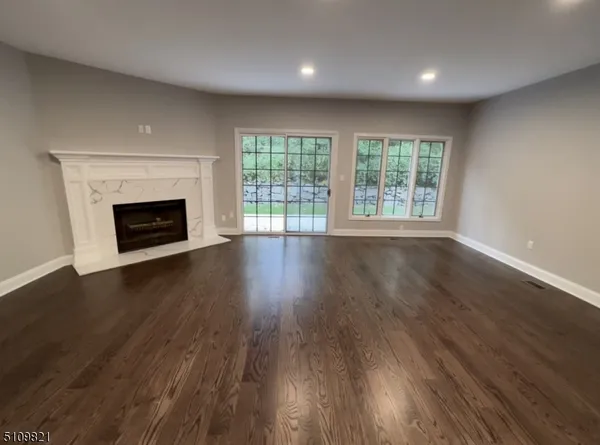 an empty room with wooden floor fireplace and windows