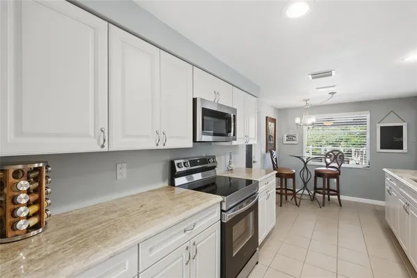 a kitchen with stainless steel appliances granite countertop a sink dishwasher stove and white cabinets with wooden floor