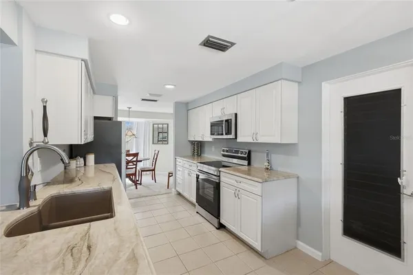 a kitchen with stainless steel appliances granite countertop a sink dishwasher stove top oven and refrigerator