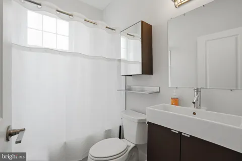a bathroom with a sink vanity mirror and toilet