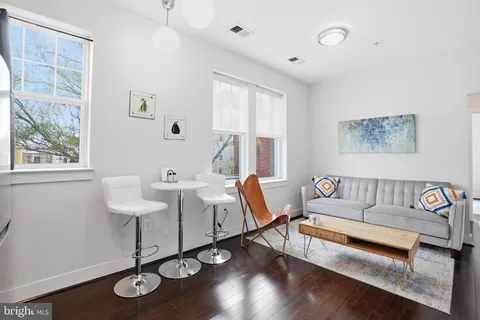 a living room with furniture a wooden floor and next to a window