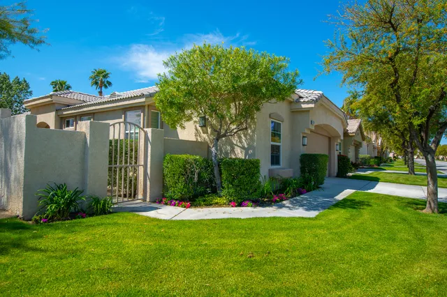 a front view of a house with a yard and palm trees