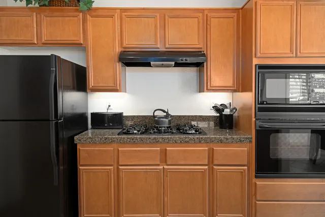 a kitchen with granite countertop a refrigerator sink and cabinets