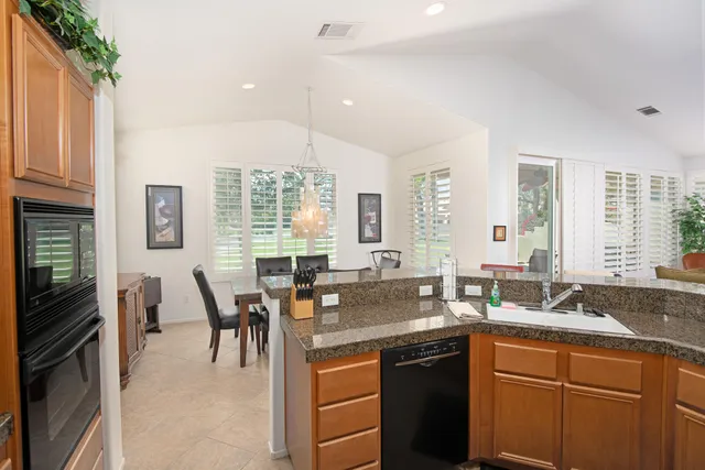a kitchen with granite countertop a sink a stove a dining table and chairs