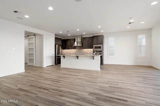 a view of a kitchen with kitchen island wooden floor center island and stainless steel appliances