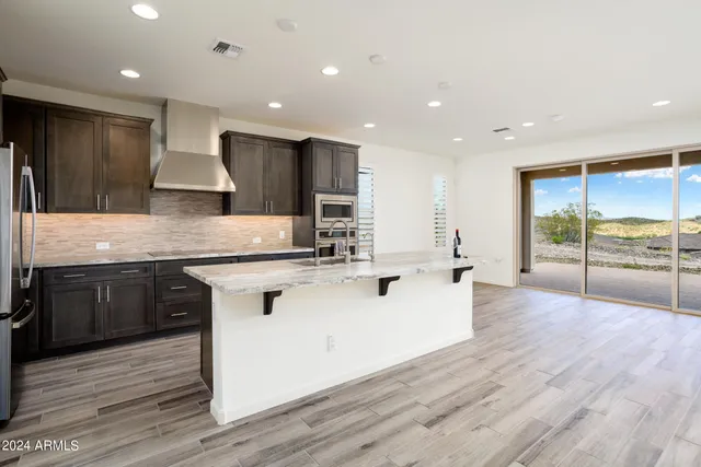 a large kitchen with stainless steel appliances granite countertop a lot of counter space and wooden floors