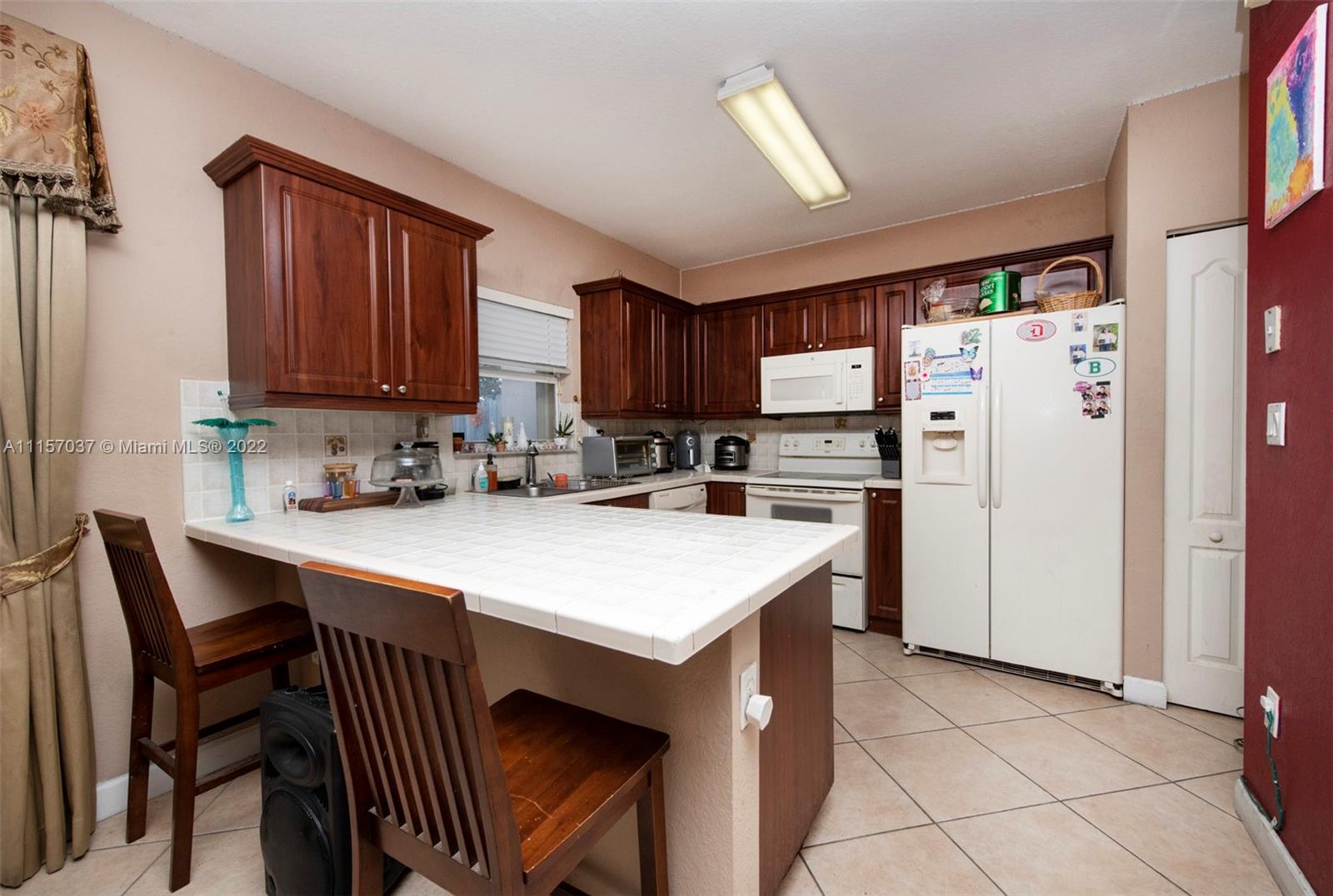 14738 Southwest 9th Lane Miami, FL 33194 - Photo 9 of 30 a kitchen with stainless steel appliances a table chairs and a refrigerator