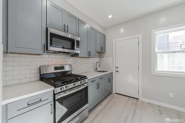 a kitchen with stainless steel appliances white cabinets granite counter tops and a window