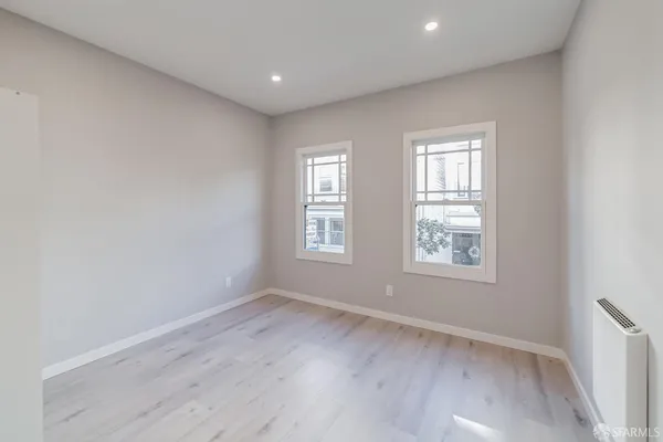 an empty room with wooden floor and windows