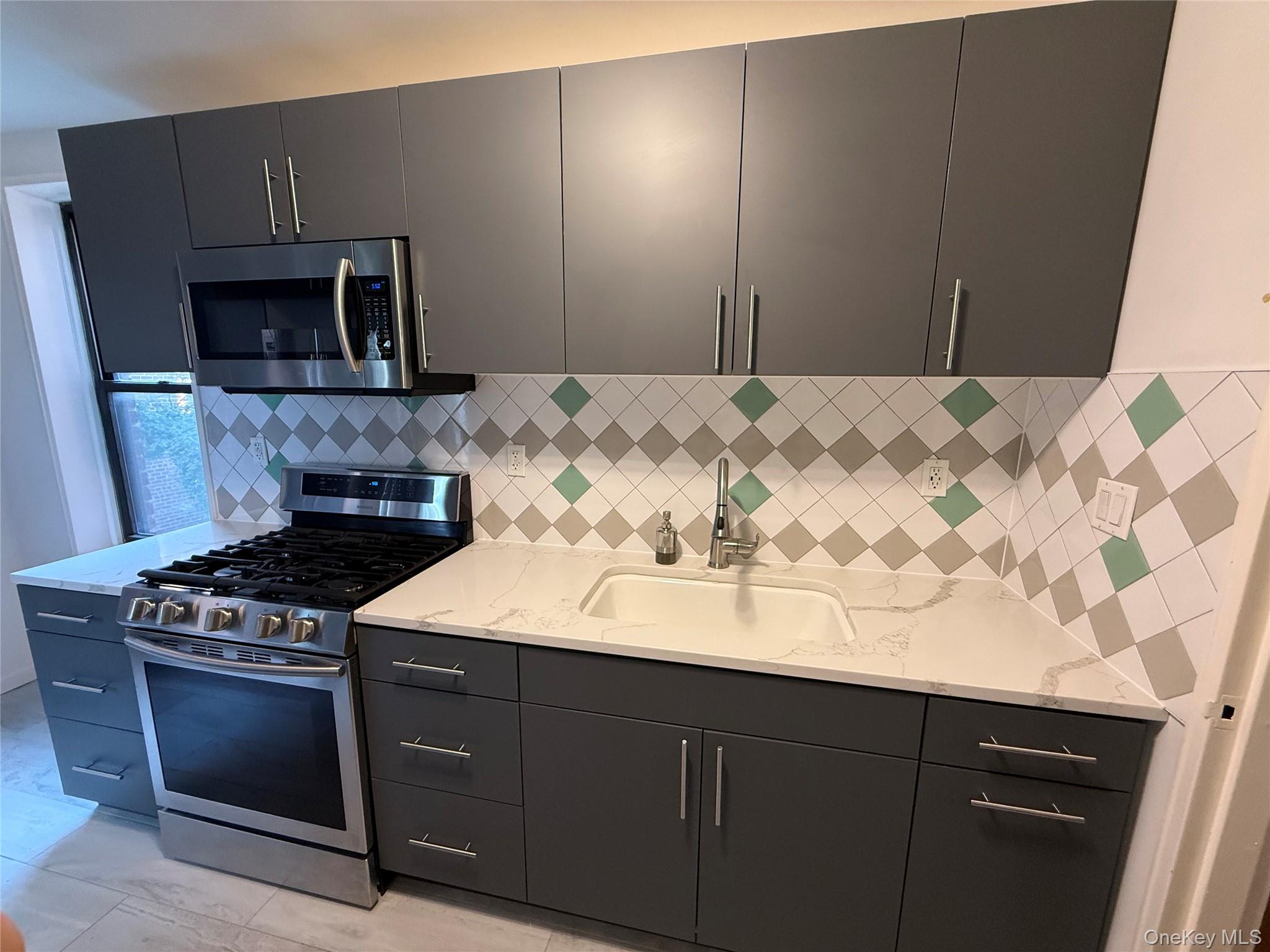 65-15 38th Avenue, Unit 5P Queens, NY 11377 - Photo 14 of 15 a kitchen with a sink stove and microwave