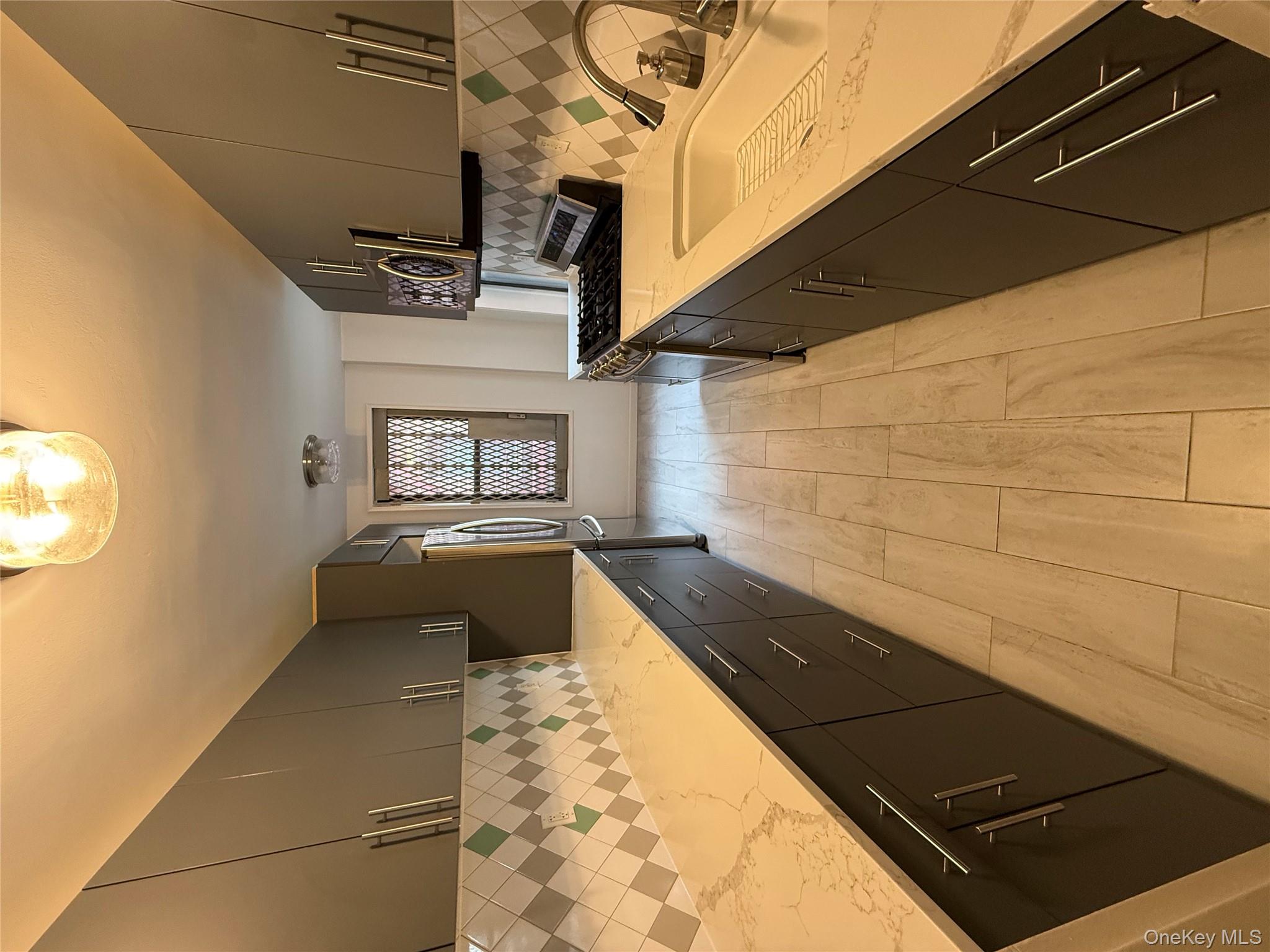 65-15 38th Avenue, Unit 5P Queens, NY 11377 - Photo 15 of 15 a large kitchen with kitchen island granite countertop a sink and wooden cabinets