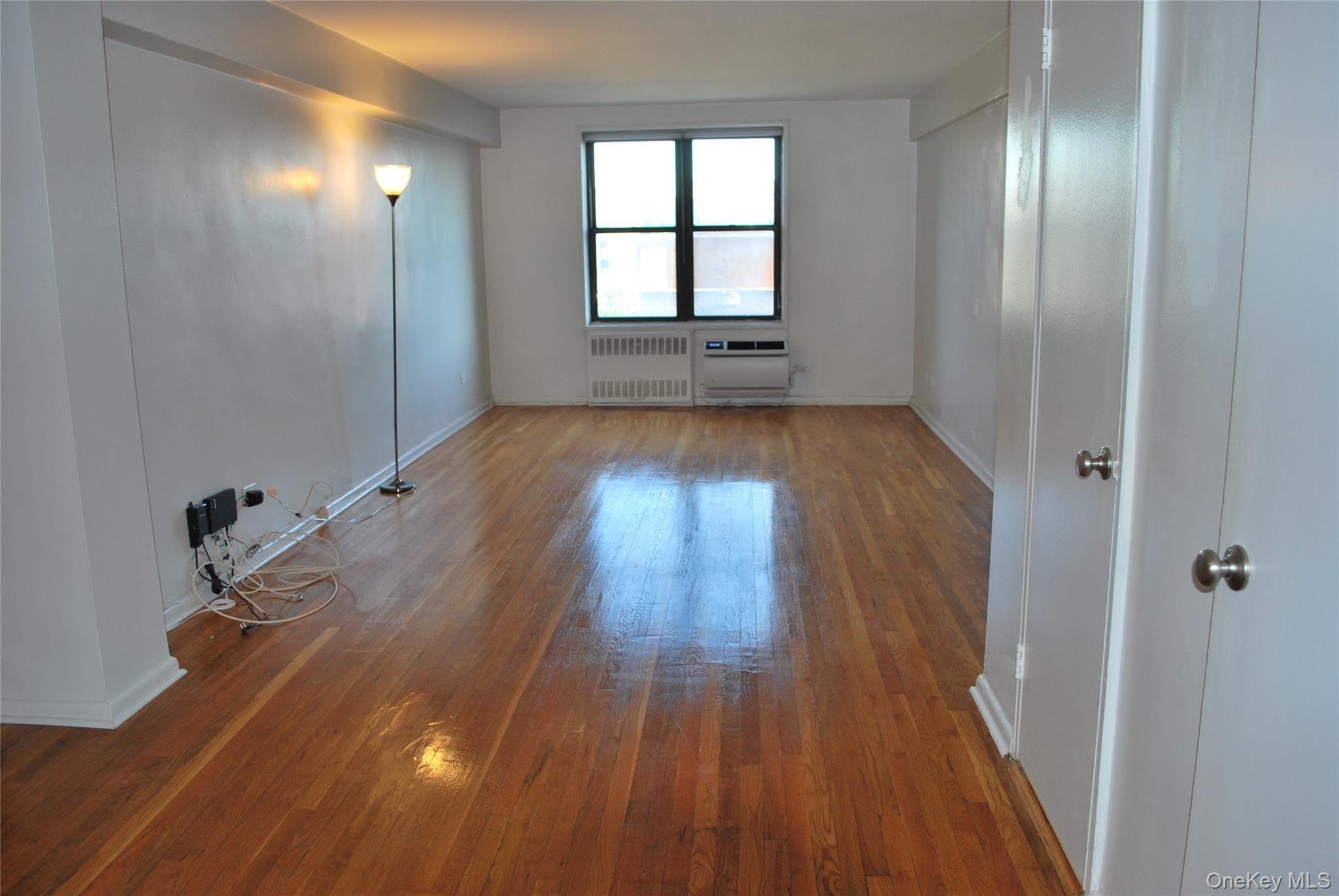 65-15 38th Avenue, Unit 5P Queens, NY 11377 - Photo 4 of 15 wooden floor in an empty room with a window