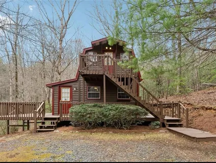a view of a house with large trees and wooden fence