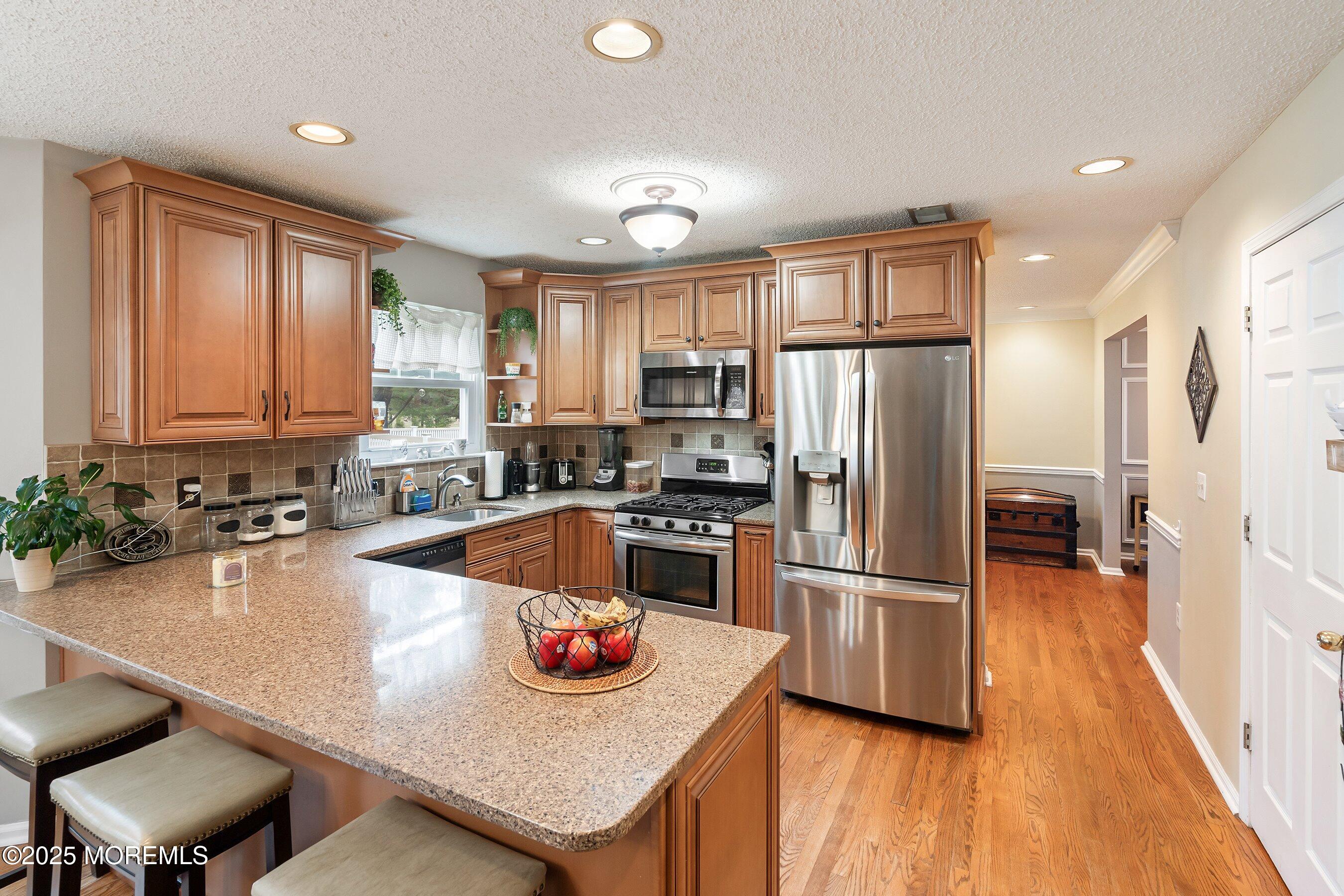 47 Crater Lake Road Howell, NJ 07731 - Photo 9 of 40 a kitchen with a refrigerator a stove a sink dishwasher a oven with wooden floor and cabinets