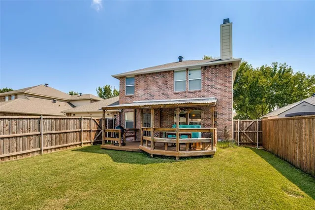 a view of a house with a wooden deck and a big yard