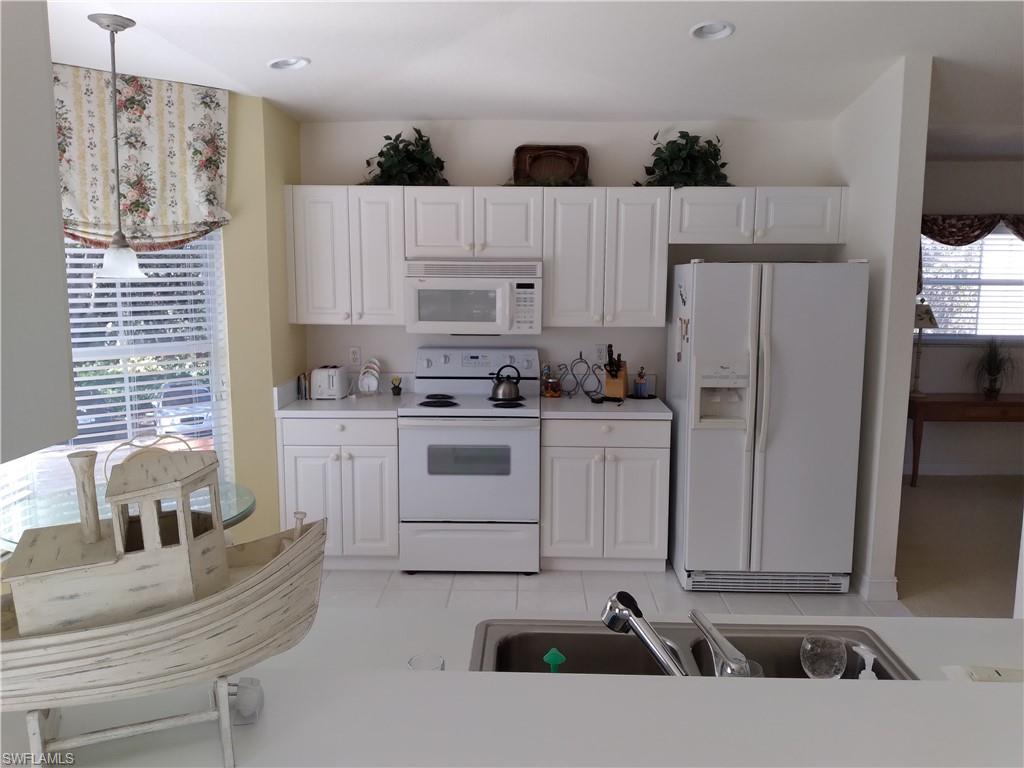 900 Diamond Circle, Unit 908 Naples, FL 34110 - Photo 8 of 22 a kitchen with a white cabinets and white appliances