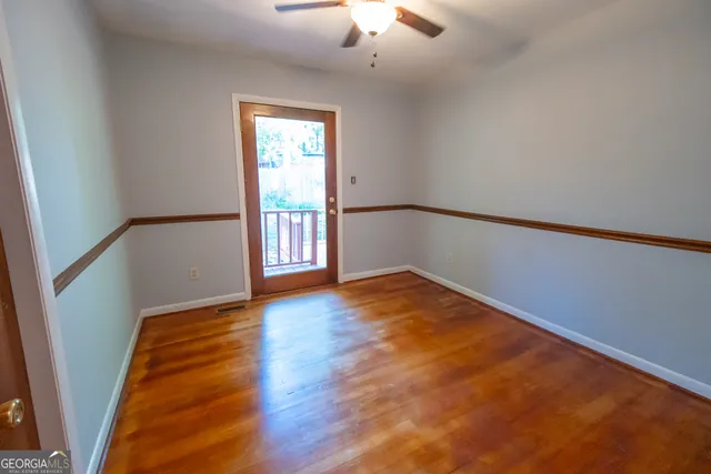 an empty room with wooden floor fan and windows