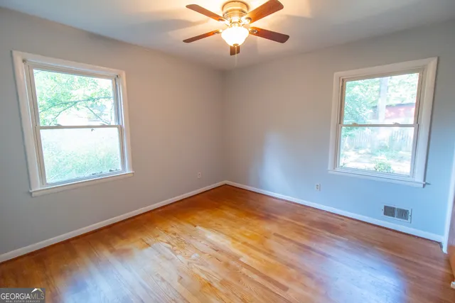 a view of an empty room with wooden floor and a window