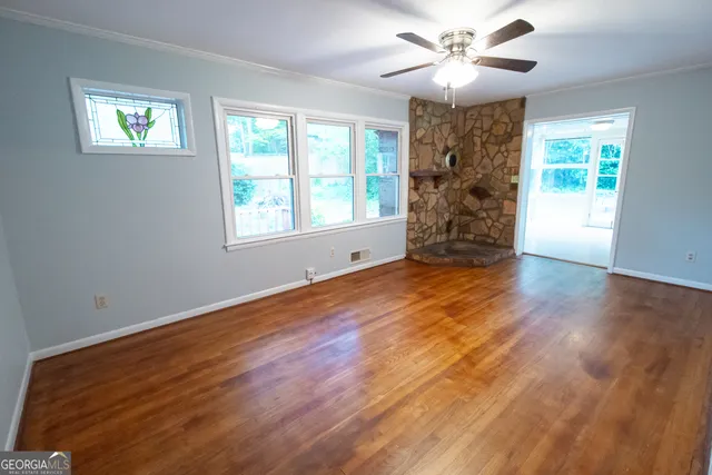 a view of an empty room with a window and wooden floor