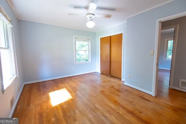 a view of empty room with wooden floor and fan