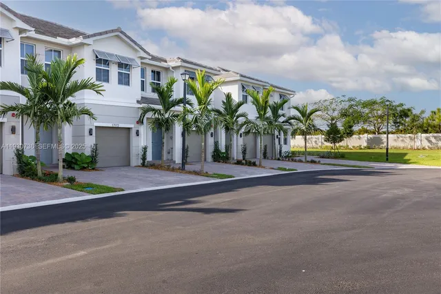 a view of a house with a big yard and palm trees