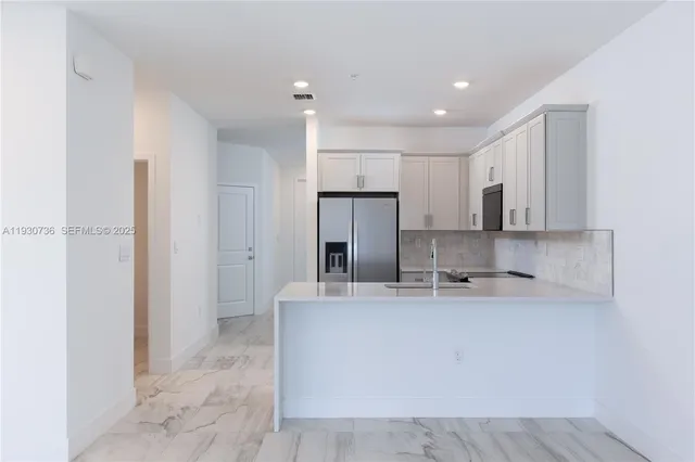 a view of a kitchen with kitchen island a sink stainless steel appliances and cabinets