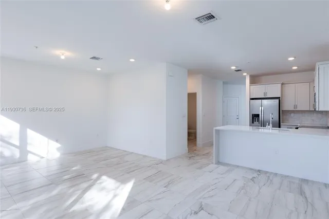 a view of kitchen with stainless steel appliances refrigerator stove and wooden floor
