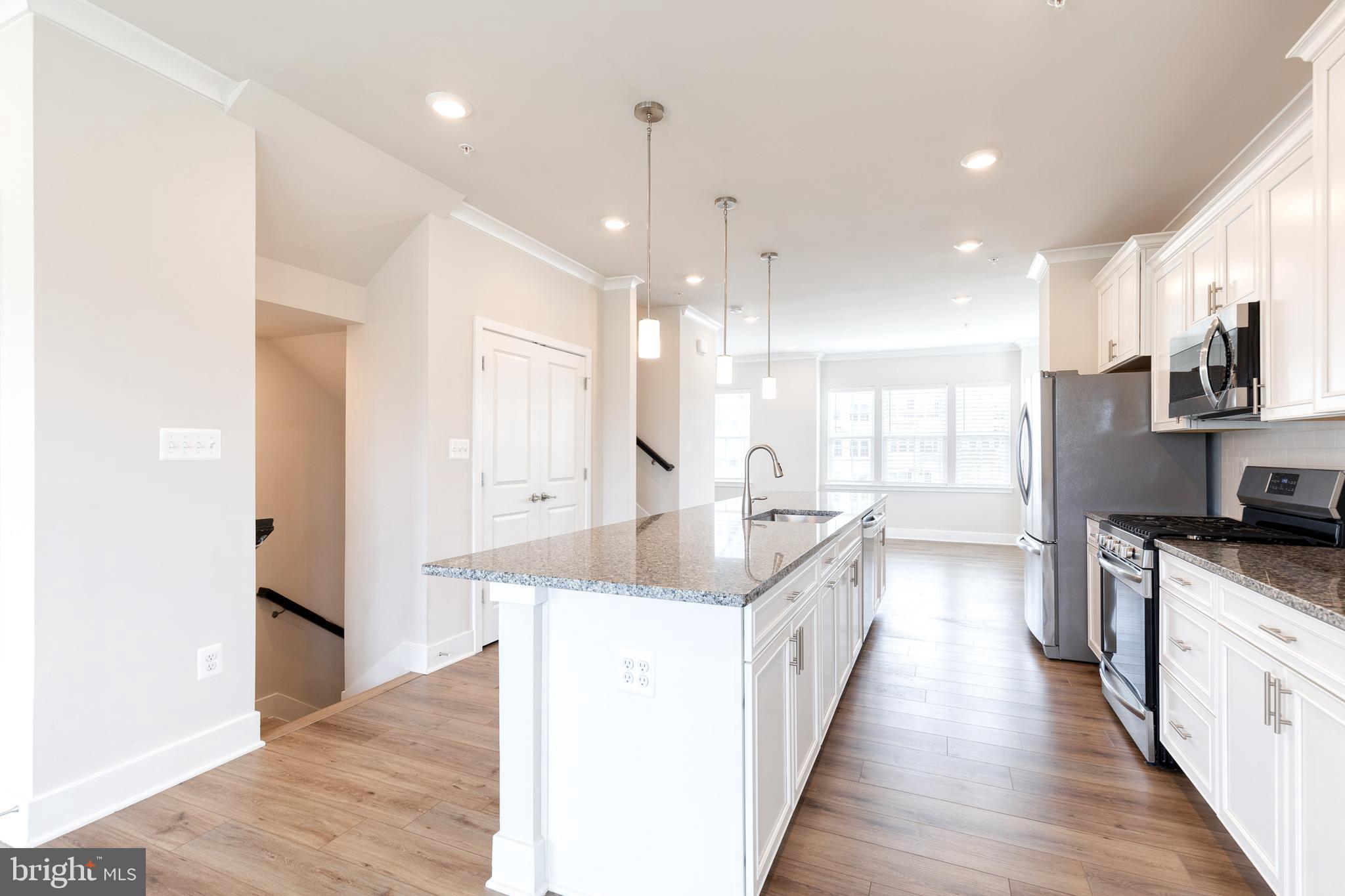 2008 Ivory Brook Road Baltimore, MD 21244 - Photo 15 of 35 a large kitchen with stainless steel appliances kitchen island granite countertop a sink and a wooden floor