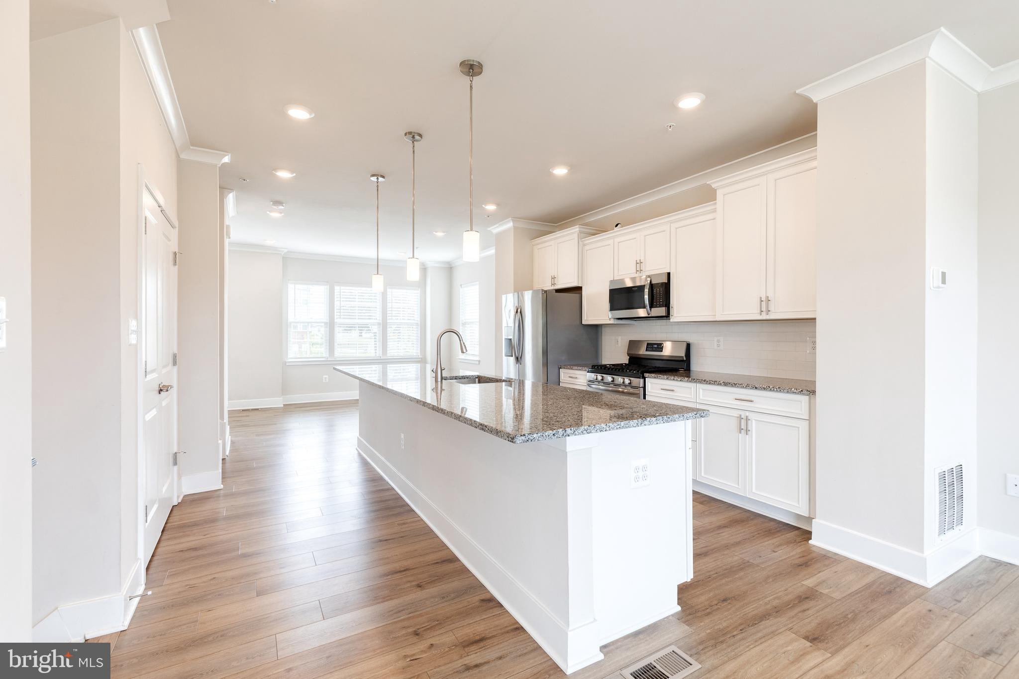 2008 Ivory Brook Road Baltimore, MD 21244 - Photo 16 of 35 a kitchen with stainless steel appliances kitchen island granite countertop a stove top oven a sink a refrigerator and white cabinets with wooden floor