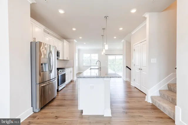a large kitchen with a center island wooden floor stainless steel appliances and windows