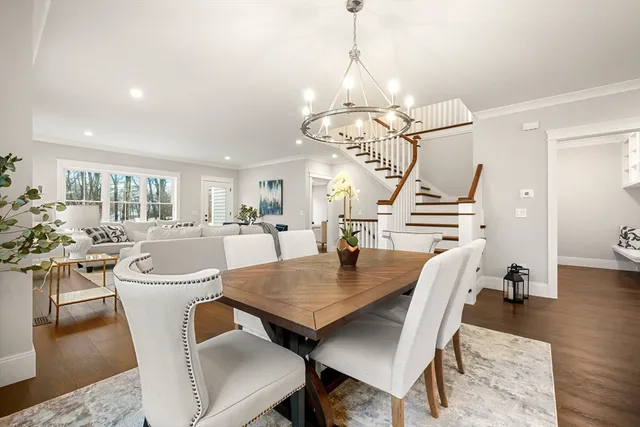 a dining room with wooden floor a chandelier a wooden table and chairs