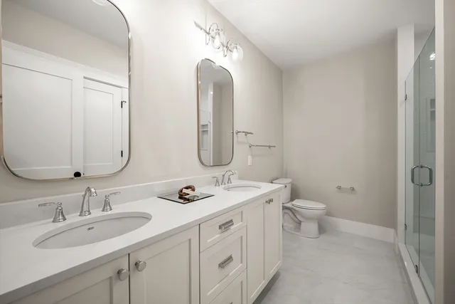 a bathroom with a double vanity sink mirror and toilet