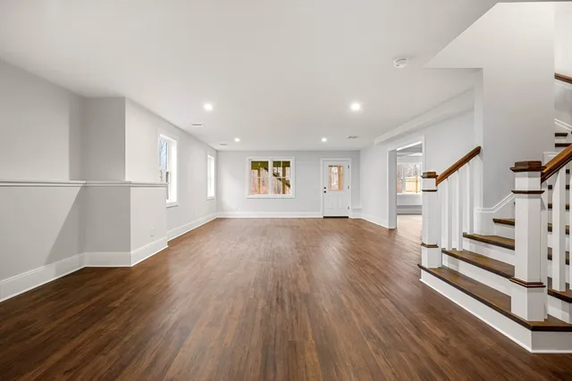 a view of an empty room with wooden floor and stairs