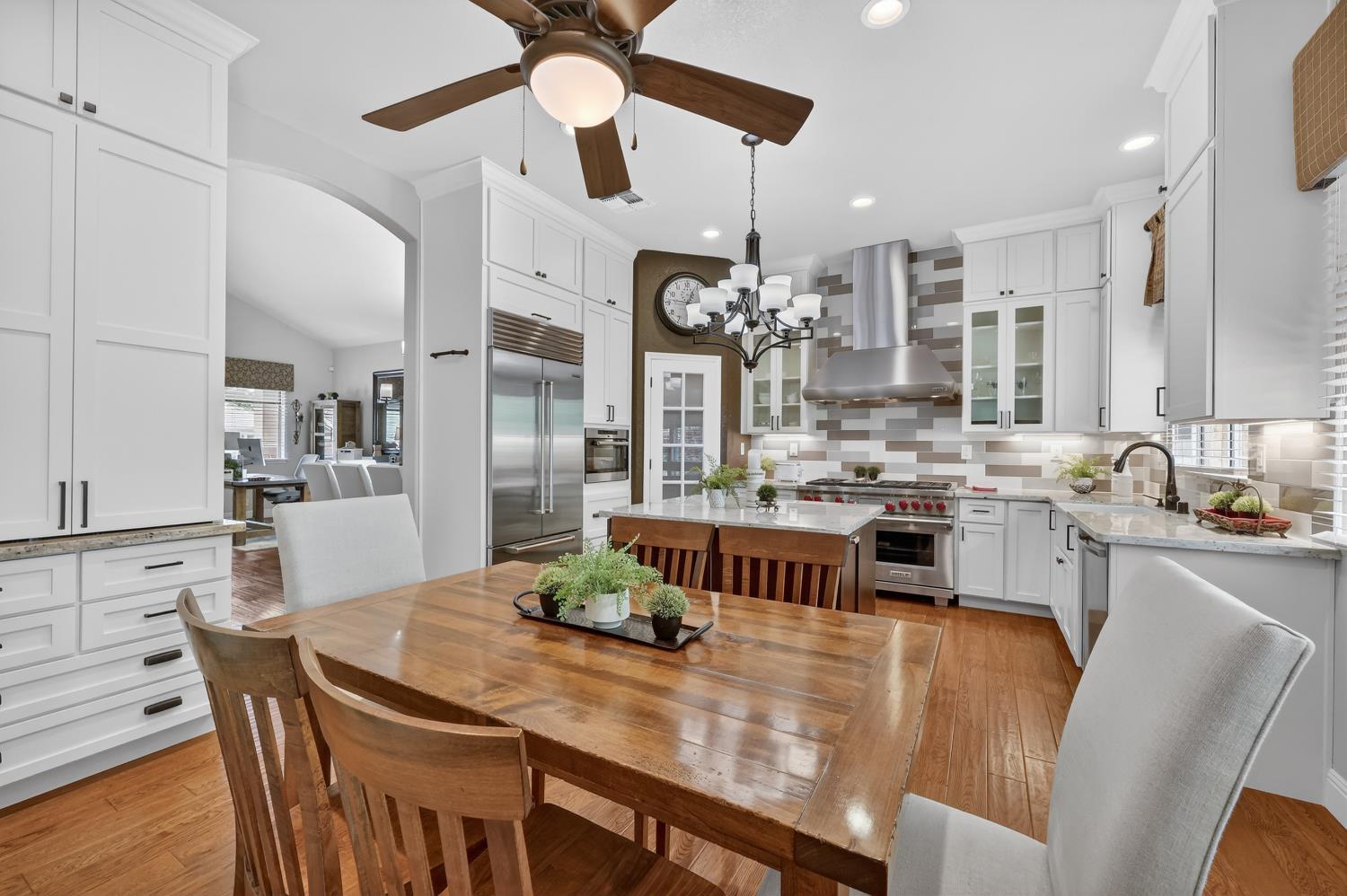 1203 Halidon Way Folsom, CA 95630 - Photo 15 of 98 a kitchen with stainless steel appliances kitchen island granite countertop a dining table chairs and white cabinets
