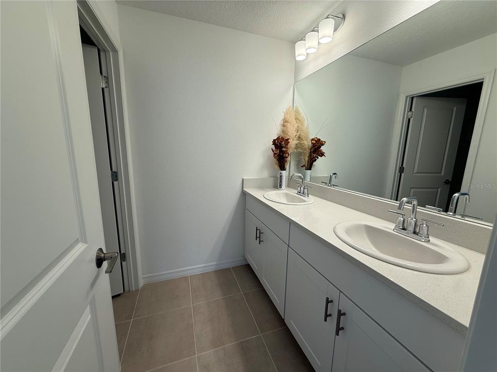6431 Milestone Loop Palmetto, FL 34221 - Photo 19 of 28 a bathroom with a double vanity sink a mirror and a shower