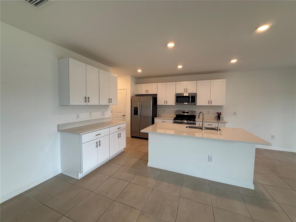 6431 Milestone Loop Palmetto, FL 34221 - Photo 6 of 28 a large kitchen with stainless steel appliances granite countertop a stove a sink a refrigerator and a microwave