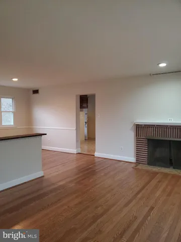 a view of empty room with wooden floor and fireplace