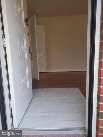 a view of an empty room with wooden floor fireplace and a window