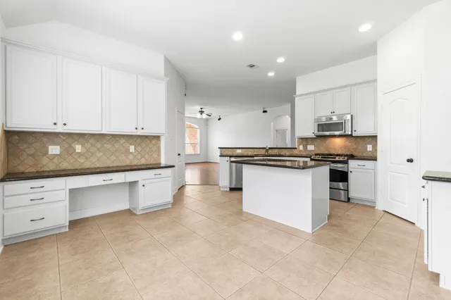 a kitchen with granite countertop a stove top oven a sink a counter space and cabinets