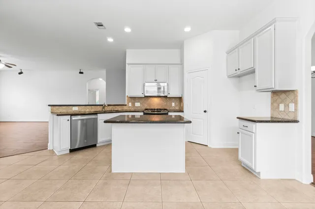 a kitchen with granite countertop white cabinets and stainless steel appliances