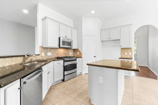 a kitchen with granite countertop a sink stove and refrigerator