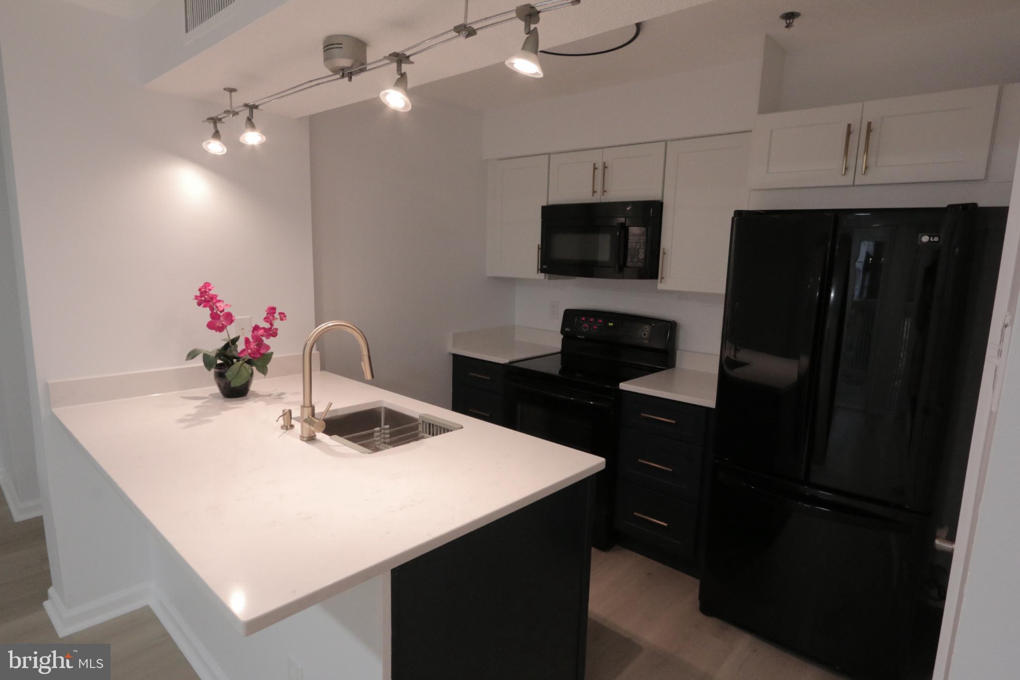 1504 Lincoln Way, Unit 104 McLean, VA 22102 - Photo 12 of 40 a kitchen with a sink a microwave a refrigerator and cabinets