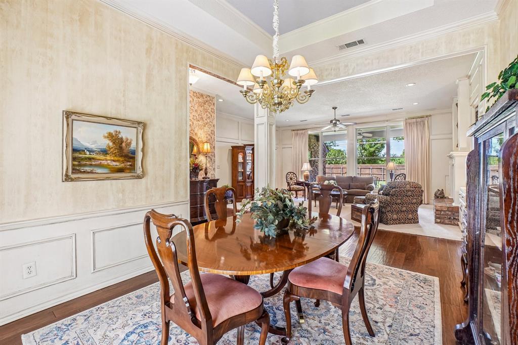 12929 Jasoncrest Trail Dallas, TX 75243 - Photo 7 of 38 Formal dining area featuring a tray ceiling, wainscoting, wood-finish flooring, and an ornate chandelier