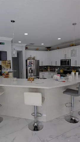 a kitchen with stainless steel appliances kitchen island granite countertop a sink and a white cabinets