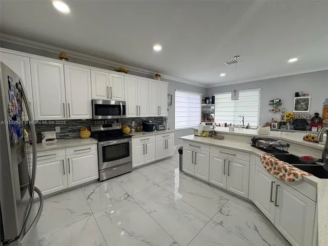 a kitchen with granite countertop white cabinets sink and stainless steel appliances