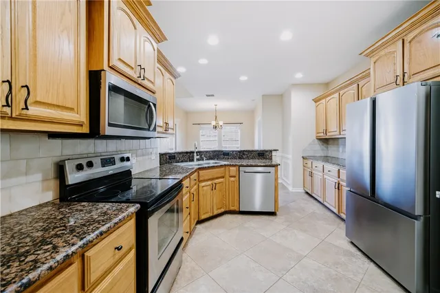 a kitchen with stainless steel appliances granite countertop a refrigerator and a stove top oven